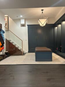 Custom cabinets CT in a modern mudroom space featuring built-in dark blue storage units, integrated bench, and elegant lighting by Mobile.