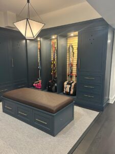 Custom cabinets CT in a modern mudroom space featuring built-in dark blue storage units, integrated bench, and elegant lighting by Mobile.