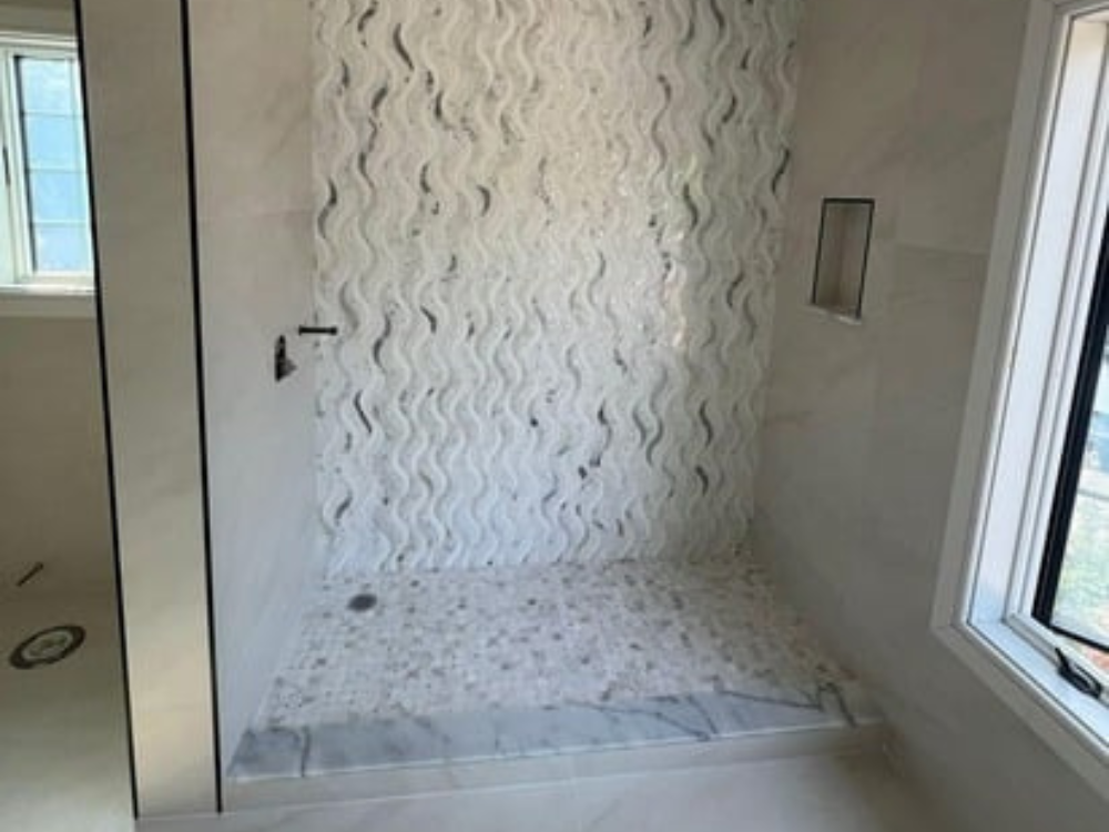 Bathroom renovation with wave-patterned tiles and modern shower design.