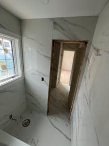 Bathroom renovation featuring marble imitation tiles and modern fixtures.
