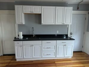 Completed kitchen renovation featuring white cabinets and black countertop