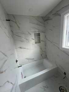 Renovated bathroom with marble imitation tiles and built-in niche.