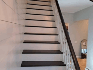 Staircase renovation featuring newly painted dark steps with a white railing.