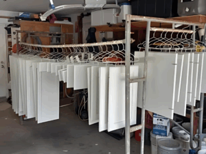Cabinet doors and drawers hanging in a garage, drying after refinishing and painting.
