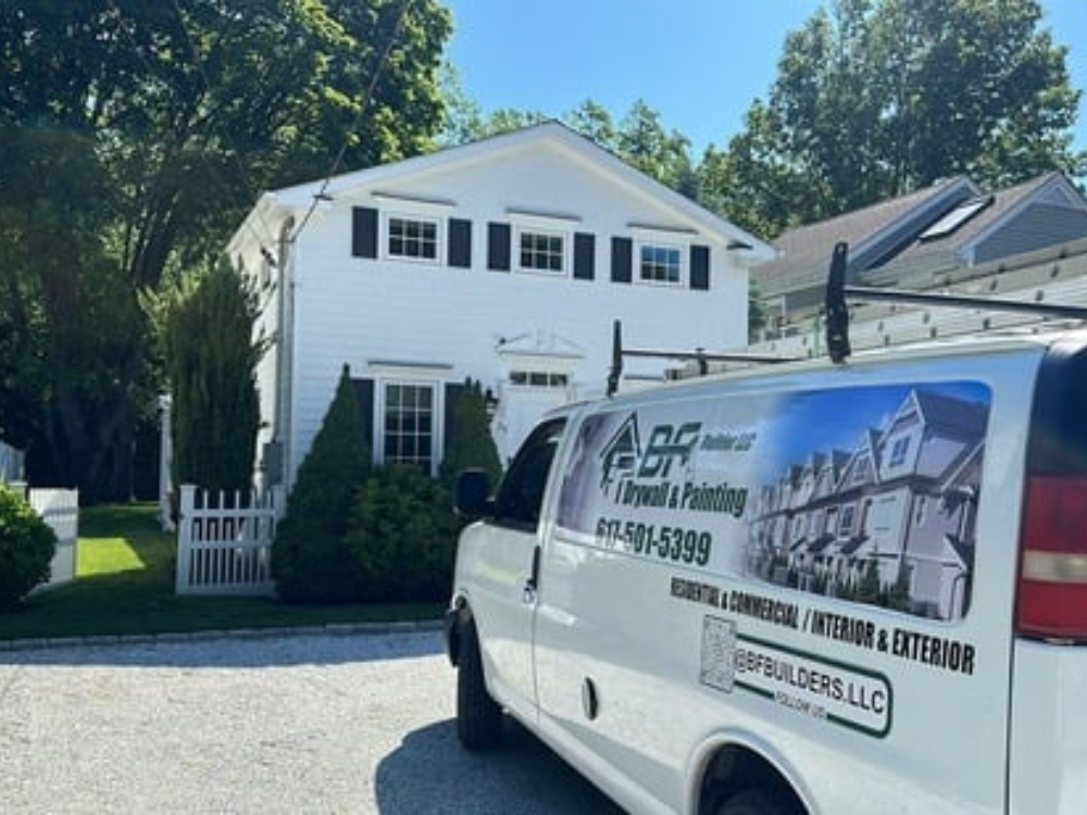 Company van parked in front of a renovated white house after exterior house renovation.