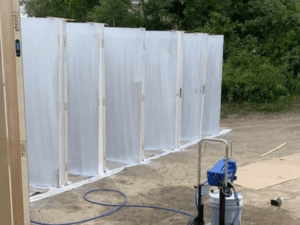Door painting preparation setup with vertical alignment and plastic sheeting.