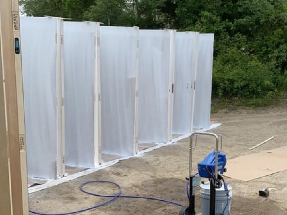 Door painting preparation setup with vertical alignment and plastic sheeting.