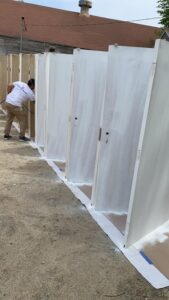 Door painting preparation in progress with a worker using a spray system.