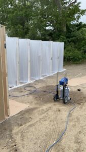 Door painting preparation area with spray equipment and lined doors.