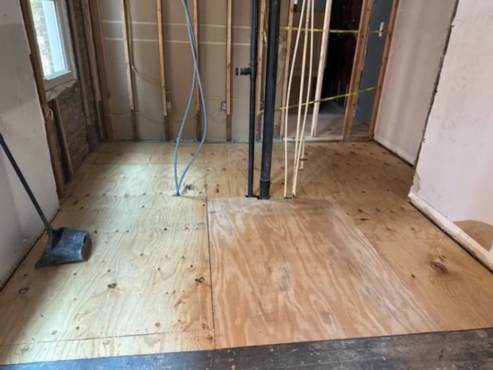 Subfloor replacement progress with new plywood installation.