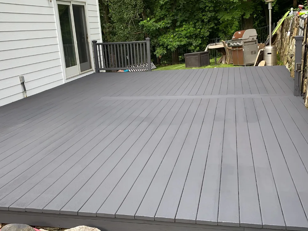 Deck refinishing and exterior painting on newly coated gray deck surface.