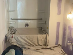 Bathroom drywall repair and preparation with bathtub protected during surface work