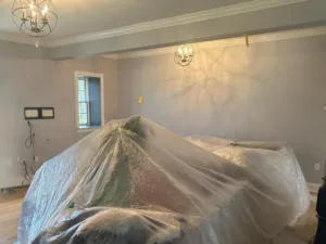 Interior painting project with furniture fully covered and walls prepared for painting