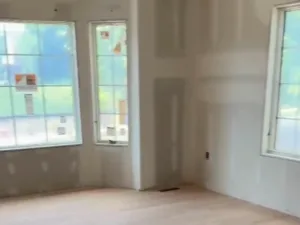 Drywall room under construction with bay windows showing precision drywall installation
