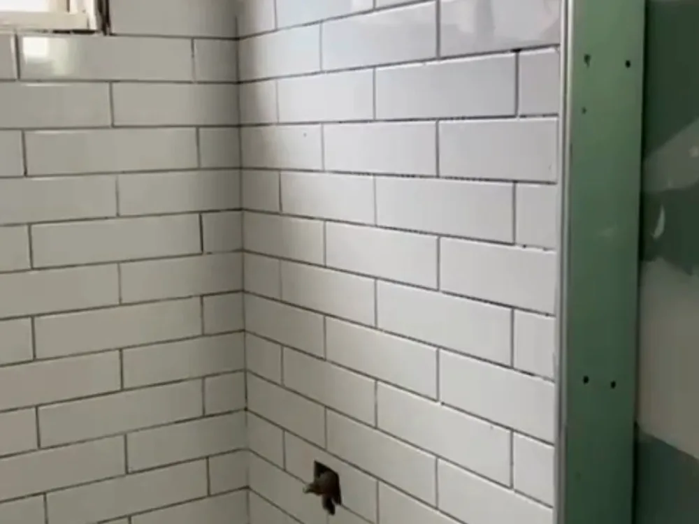 Subway tile shower installation showing wall preparation, waterproofing membrane, and tile spacers before grouting.